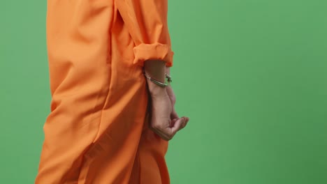 vista lateral de cerca de las manos del prisionero masculino en esposas mientras camina en el fondo de la pantalla verde