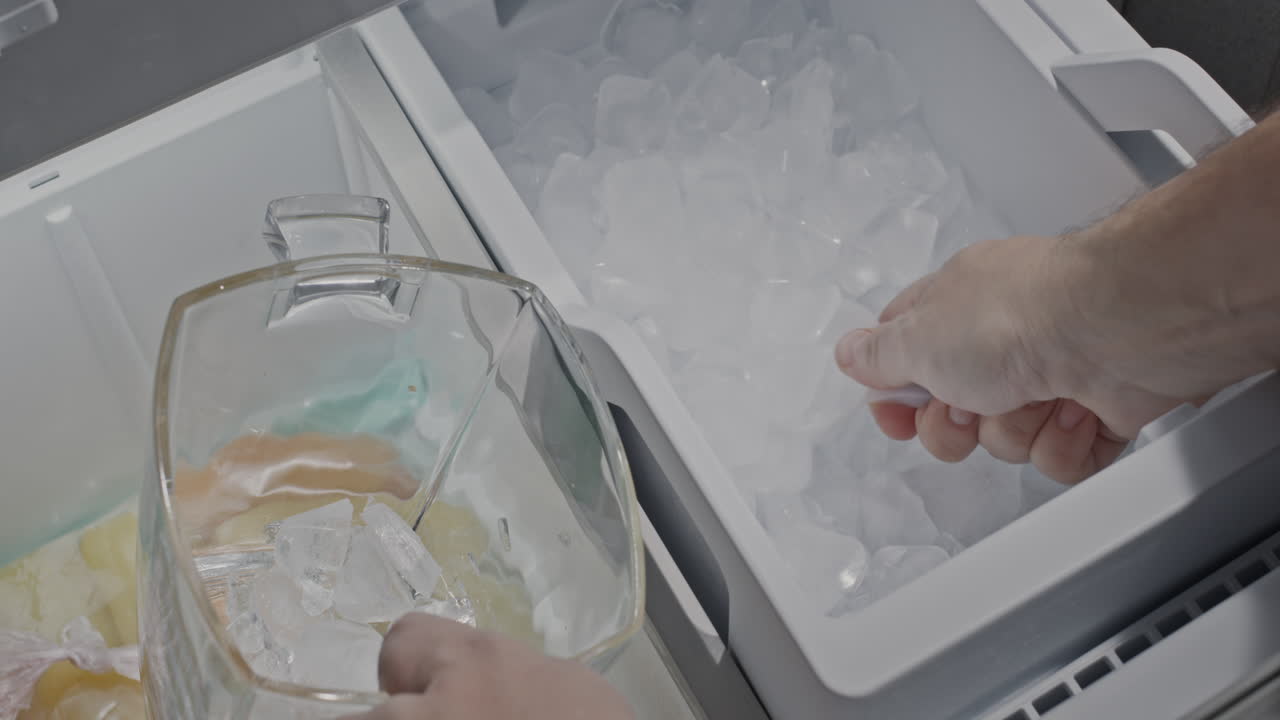un hombre recoge hielo de la heladera de un refrigerador doméstico