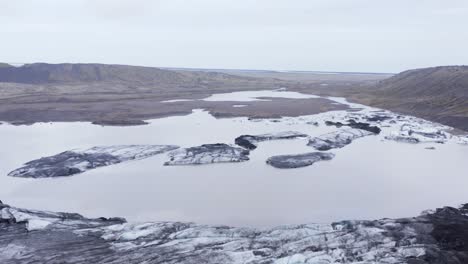 calved icebergs in glacial lagoon at kvíarjökull glacier on cloudy day, aerial