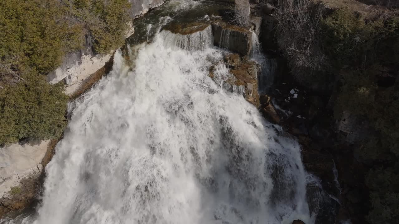 The roaring owen sound waterfall surrounded by lush greenery in ontario, canada, aerial view