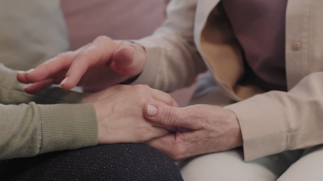 Two people holding hands in a comforting manner