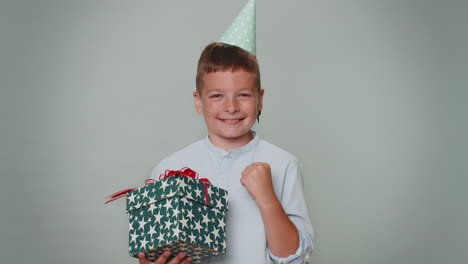 cheerful toddler kid boy opening birthday gift box, smiling joyfully, amazed satisfied with present