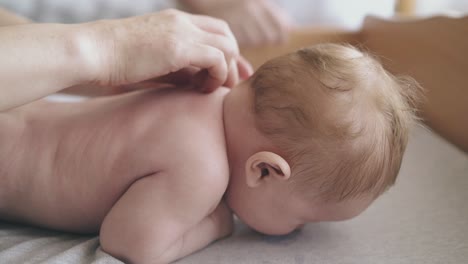 newborn boy with fair hair lies on stomach on large table