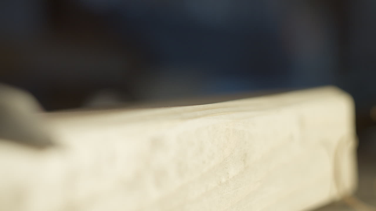 High quality video of a craftsman carving smooth curls from light wood in warm cinematic light, showing precise hand control and clean fine texture in a calm workshop atmosphere