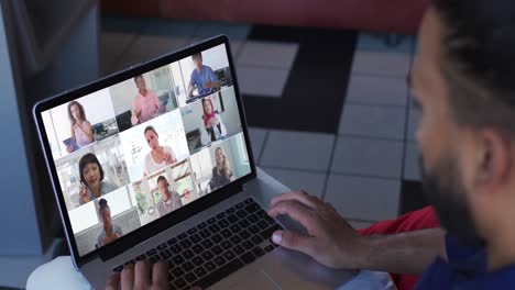 hombre afroamericano teniendo una videoconferencia con colegas de oficina en una computadora portátil en casa