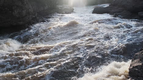 Fast-moving-river-rapids-through-rocky-canyon-at-sunset