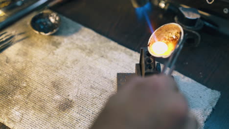 jeweler pours molten metal into form on table close view