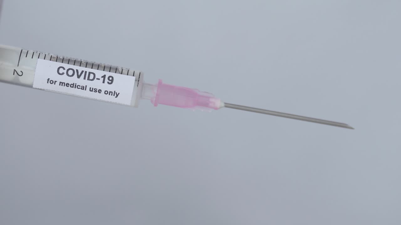 Hand With Elastic Glove Removes The Needle Cap Of Syringe With COVID-19 Vaccine - For Medical Use Only