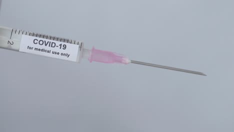 hand with elastic glove removes the needle cap of syringe with covid-19 vaccine - for medical use only