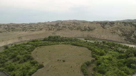 meandering alazani river flowing around circular peninsula with trees