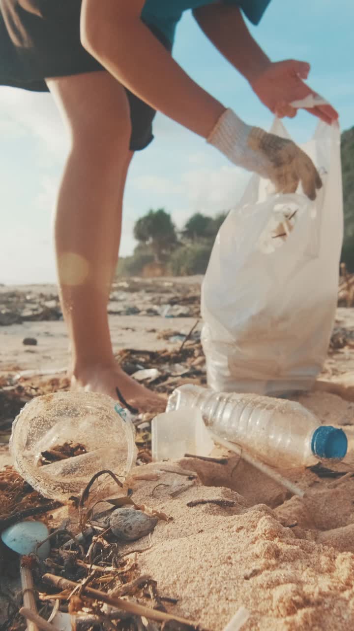 Cropped woman environmental activist wearing gloves alone cleans sea beach
