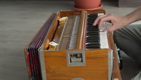 man playing a harmonium, a traditional indian musical instrument