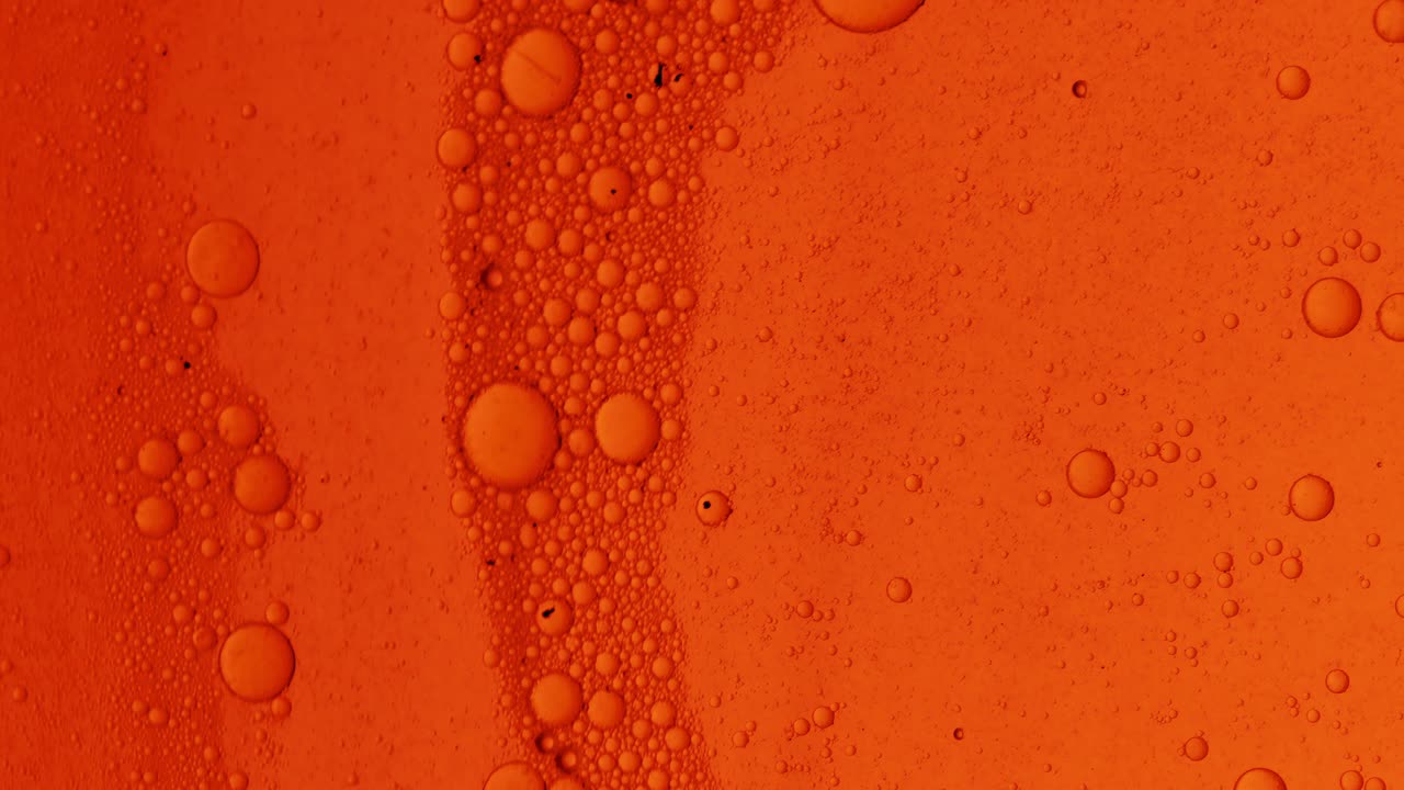 표면에 거품과 먼지가 있는 검은 반점이 있는 더러운 주황색 오일 흐름