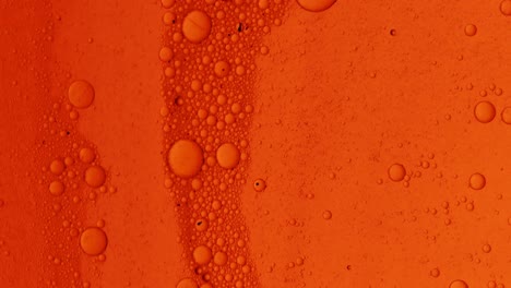 dirty orange oil flow with black spots slowly with bubbles and dust on surface