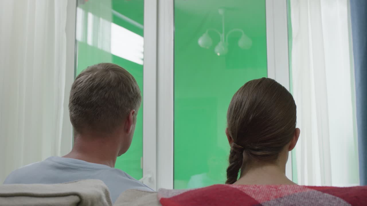 커플이 녹색 화면 창을 보고 있습니다.