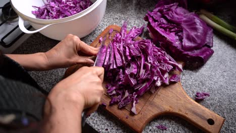 chopping red cabbage on wooden chopping board at the kitchen