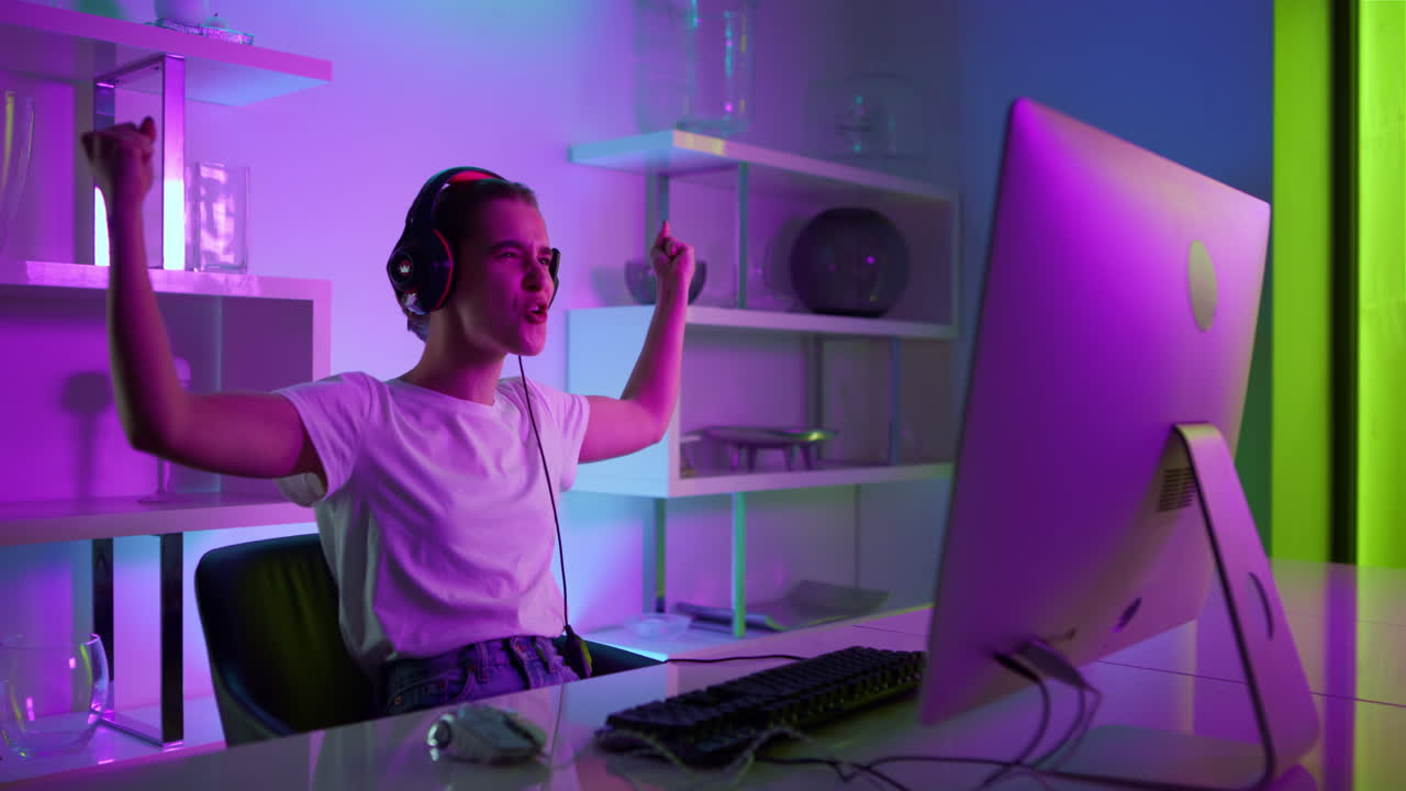 Nahaufnahme einer schönen Spielerin, die zu Hause in Neonlichtern einen Online-E-Sport-Wettbewerb gewinnt.