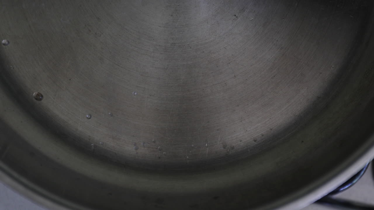 замедленное изображение капель, мягко брызгающих в кастрюлю, постепенно собирающихся вместе, чтобы сформировать более крупные капли