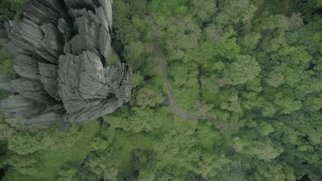 Aerial-top-down-view-of-road-amidst-dense-greenery-leading-to-unusual-rocks-formation-at-Yana-caves-in-Karnataka