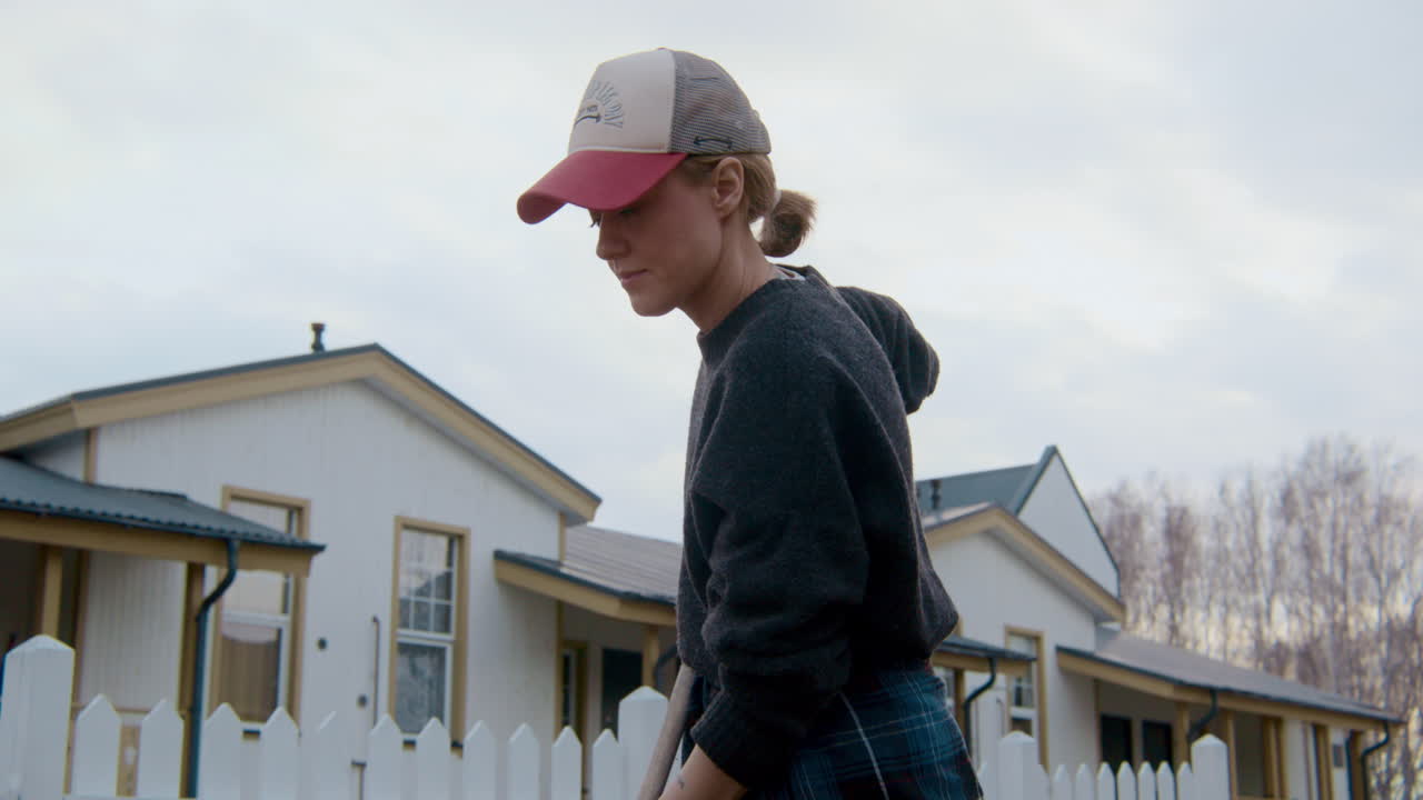 Woman Gardening in Front of Homes