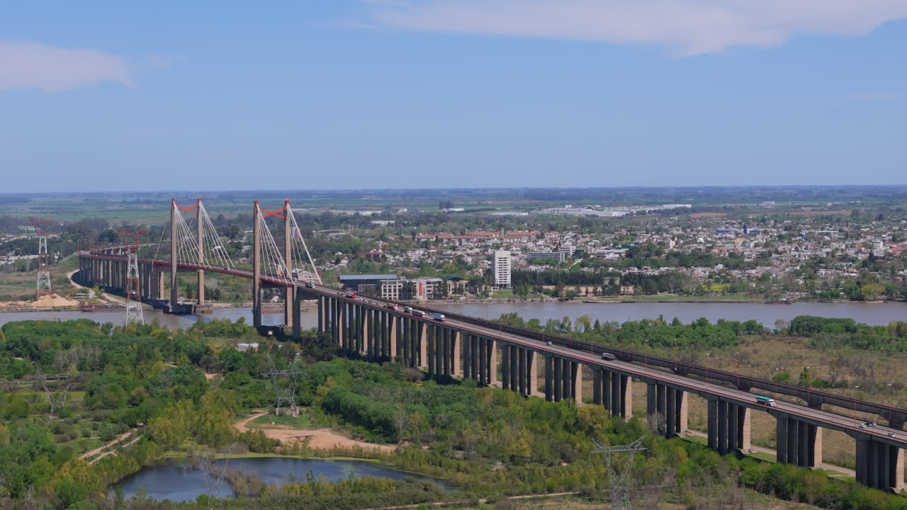 Aerial view of suspension bridge Zárate Brazo Largo over Paraná River with city in background, Argentina