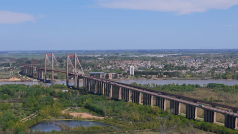 aerial view of suspension bridge zárate brazo largo over paraná river with city in background, argentina