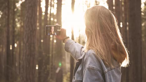 young girl taking photo at smartphone in forest