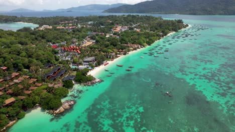 Costa-De-Koh-Lipe,-Tailandia,-Con-Barcos-Atracados-Y-Aguas-Turquesas-Con-Arrecifes-De-Coral,-Vuelo-Aéreo