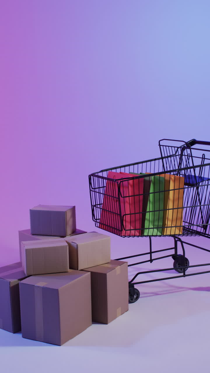 Vertical video of shopping trolley and shopping with copy space over pink neon background