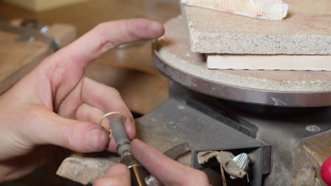 diamond gold wedding ring in the making and getting polished on the inside by jeweller