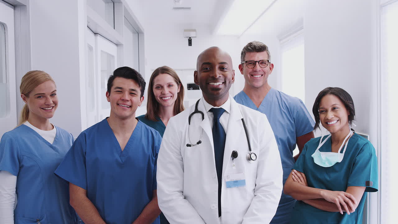Retrato de Equipe Médica Multicultural Sorrindo em Pé em Corredor de Hospital
