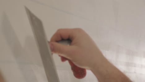 man plastering the walls with finishing putty in room with putty spatula