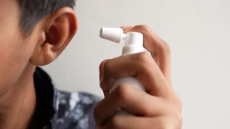 Close-up-of-men-using-spray-to-remove-earwax