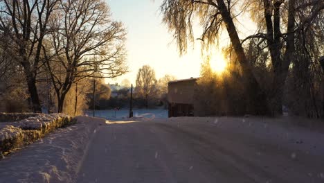 Eisige-Straße-Und-Sonne-Scheinen-über-Ländlichem-Dorf,-Während-Es-Schneit,-Dolly-Vorwärts