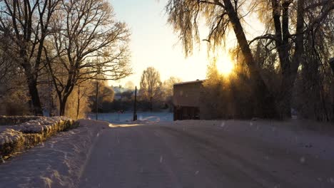 carretera helada y el sol brillando sobre el pueblo rural mientras nieva, dolly hacia adelante