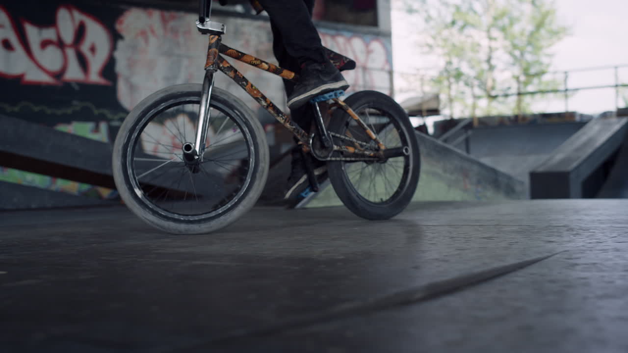 Wysportowany mężczyzna jeżdżący na rowerze BMX w skateparku. Rowerzysta BMX wykonujący trik na zewnątrz
