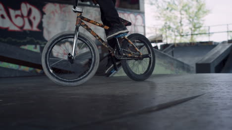 Sporty-man-riding-bmx-bike-at-skatepark.-Bmx-rider-performing-trick-outdoors.