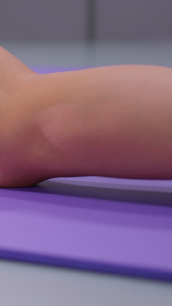 primer plano de estiramiento de piernas realizado en una alfombra de yoga púrpura, mostrando pierna y pie en calcetines blancos, enfatizando el detalle y la tensión durante una sesión de entrenamiento