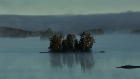 aerial view of fog sets in around lone island on lake