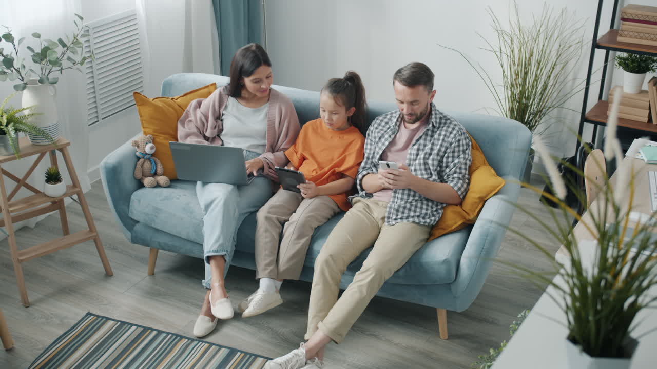 Family relaxing on a couch with technology