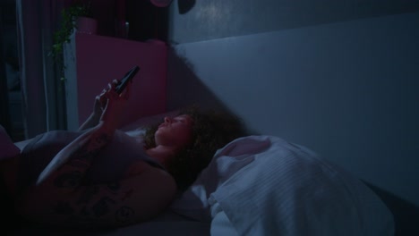 persona que usa un teléfono en la cama por la noche