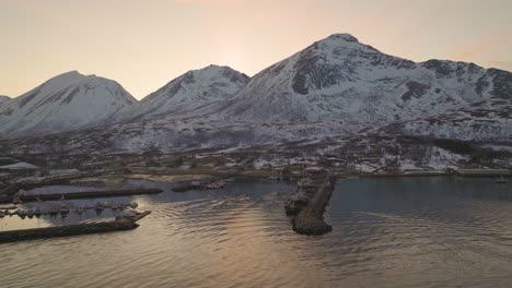 local fishing boat returns to harbour from arctic waters, sunset snowy mountains