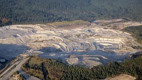 Aerial-View-of-Giant-Quarry-in-Forested-Landscape---Sunny-Day