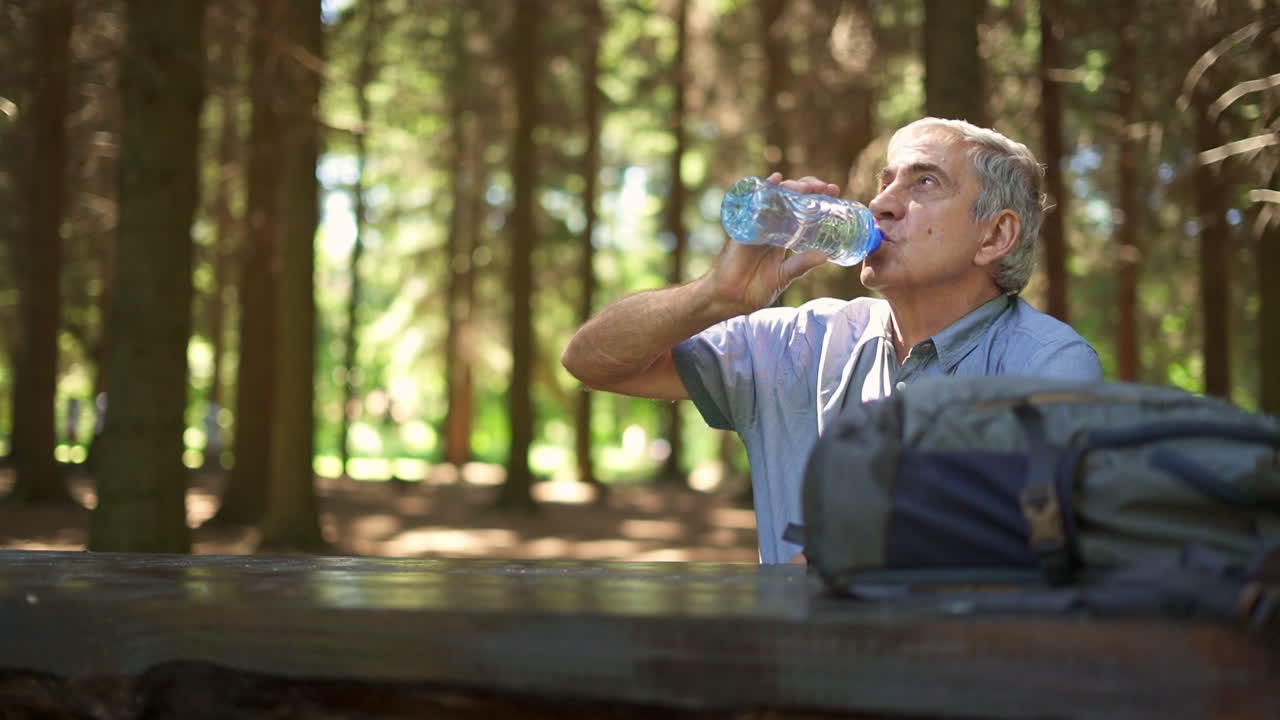 Senior man drinking water in forest