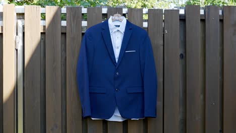 The-groom's-suit-hangs-ready-on-a-garden-fence-for-the-wedding-day