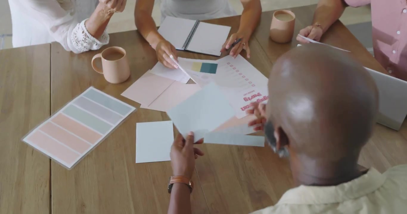 Design team sorting pastel swatches on table with green code overlay guiding color decision