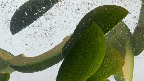 líquido de aguacate cortado en primer plano en fondo blanco. piezas de verduras flotantes.