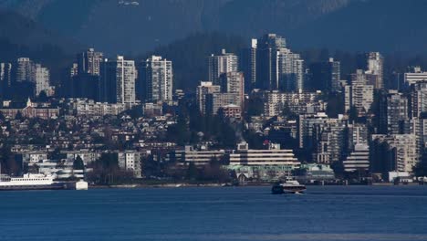 seabus sailing on the water with in the background the city of vancouver on a sunny day