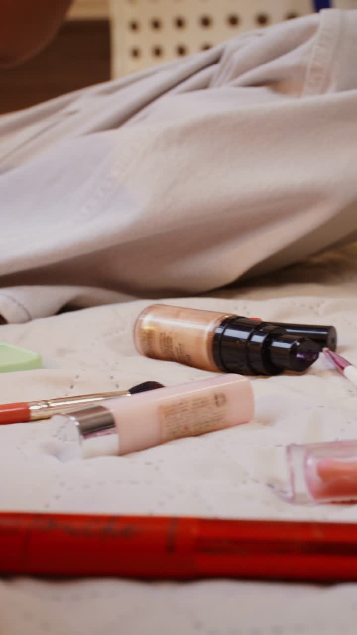 Woman getting ready with makeup on a bed