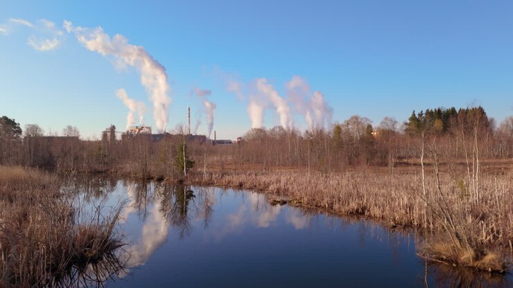 Drone view over river with reflection of greenhouse gases emitted from factory